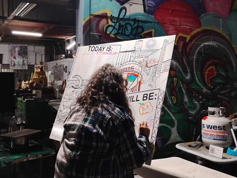 Fellow vendor Dayana with “Reap & Sow Co.” drawing on the interactive piece.